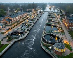 Aerial view of large water treatment plant with circular clarifiers and industrial buildings along river at dusk photo