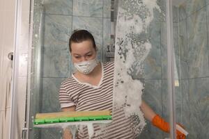 A diligent woman is thoroughly cleaning the shower using soap and a scrubbing tool photo