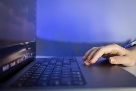 An anonymous user's hand navigates a laptop's trackpad, symbolizing effective remote work, engaged digital learning, and streamlined technological interaction at night photo