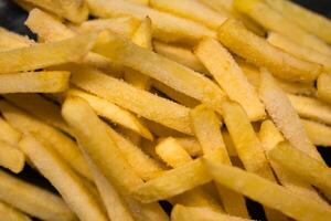 Vibrant golden frozen french fries, showcasing uncooked potato sticks visibly covered with frosty ice crystals, ideal for convenient quick preparation of delicious fast food photo