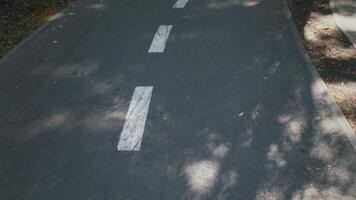 Pov shot of runner walking on sports path in public urban park, tracking shot over asphalt road, slow motion video