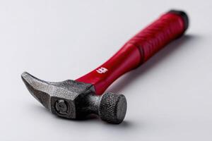 Claw hammer with a red rubber grip on white backdrop photo