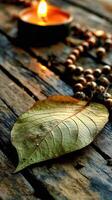 Fallen leaf and prayer beads adorn weathered wood with burning candle photo