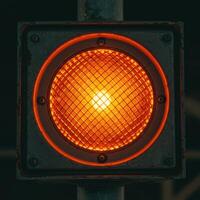 Close up of a single glowing orange traffic signal light with a textured lens photo
