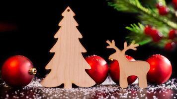 Wooden toy deer and spruce on a dark table with white snow photo