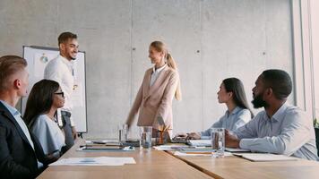 A professional setting reveals a confident presenter leading a business discussion. Team members actively participate, exchanging ideas around a table filled with documents and glassware. video
