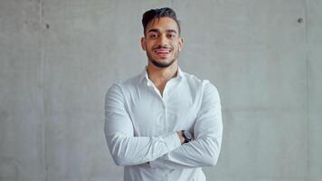 A young professional Middle Eastern man stands confidently in a contemporary office setting. He displays an air of determination and success. Natural light enhances the modern backdrop. video