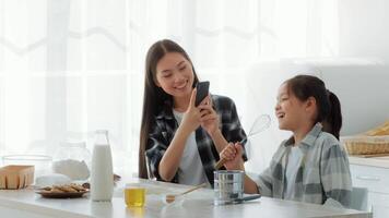 A mother and daughter enjoy precious time together in the kitchen, cooking and laughing. The bright space is filled with ingredients, emphasizing love and bonding during family activities. video