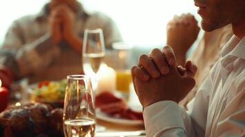 Family and friends gather around a beautifully set table, hands clasped in prayer before enjoying a festive Thanksgiving meal. The atmosphere is warm and inviting, filled with joy. video