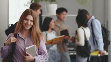 A cheerful woman posing over group of diverse students collaborates and studies together in a lively university environment. video