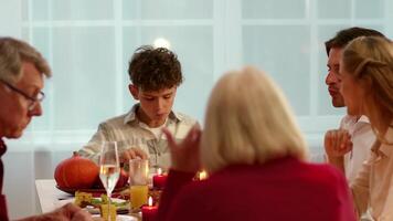 Family gathers around a table filled with Thanksgiving dishes, enjoying a festive meal. Laughter and conversation fill the air as they celebrate together in a warm, cozy atmosphere. video