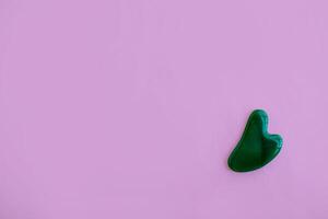 Jade massager on a pink background. Background with copy space. photo