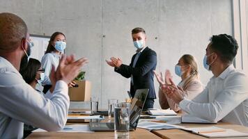 A business team gathers in a modern office for a meeting. The presenter stands, discussing strategies while colleagues attentively listen, all wearing masks for safety. video