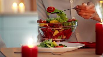 Family members prepare a vibrant salad in a cozy kitchen, surrounded by candles and festive decorations. The warm glow enhances the joyful atmosphere of Thanksgiving Day gatherings. video