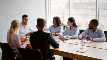 A diverse group of professionals collaborates in a contemporary office, discussing business strategies around a conference table. The atmosphere is productive and engaging. video