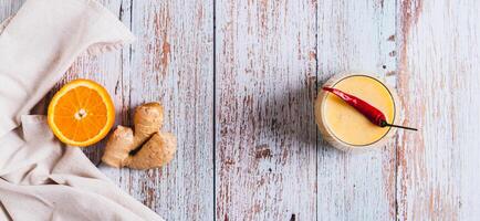 Orange ginger smoothie with pepper for weight loss in a glass top view web banner photo