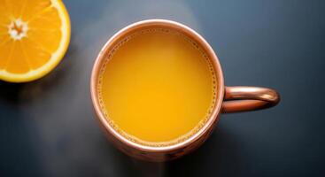 A copper mug of orange juice on a dark table photo