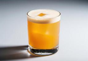 A glass of orange drink sitting on a table photo