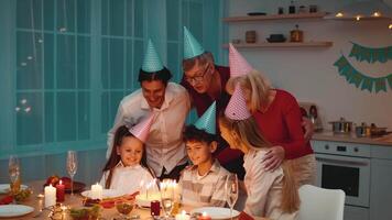 A joyful gathering of family members celebrates Birthday at home, sharing laughter and delicious food while wearing festive party hats and surrounded by candlelight. video