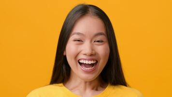 A young woman with straight, long hair smiles brightly, radiating joy and positivity. She stands against a vivid yellow backdrop, showcasing a lively and cheerful atmosphere. video
