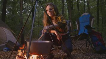 Participants breathe in the fresh air as they prepare a meal over an open fire. The surrounding forest adds tranquility, perfect for a weekend of camping and hiking. video