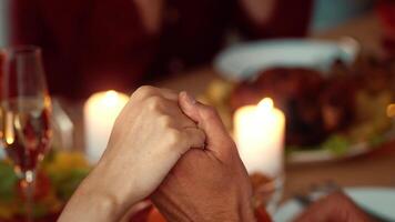 Gathered around a beautifully set table, family members hold hands in gratitude before enjoying a festive Thanksgiving meal, filling the atmosphere with warmth and joy. video
