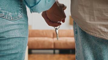 A Caucasian couple stands in their new apartment, holding keys together. They are focused on the excitement of moving into their first home amid boxes and a cozy atmosphere. video