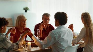 Families come together at home to celebrate Thanksgiving Day, sharing a meal filled with gratitude. Everyone holds hands, expressing appreciation before enjoying the feast. video
