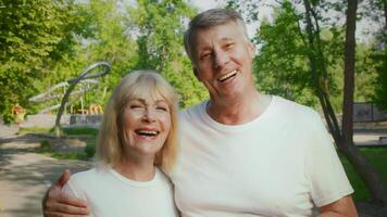 A senior couple jogs happily together in a green park, embracing an active lifestyle. Their smiles and energy highlight the joy of staying fit while enjoying nature. video