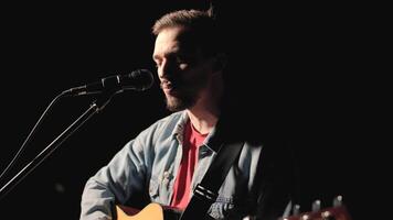 A musician is playing guitar on a large stage with audience members holding flashlights in the background. The auditorium is filled with beautiful flashing lights. 40 video