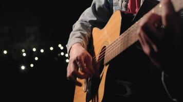 A musician is playing guitar on a large stage with audience members holding flashlights in the background. The auditorium is filled with beautiful flashing lights. 25 video