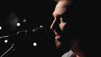 A musician is playing guitar on a large stage with audience members holding flashlights in the background. The auditorium is filled with beautiful flashing lights. 50 video