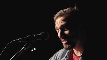 A musician is playing guitar on a large stage with audience members holding flashlights in the background. The auditorium is filled with beautiful flashing lights. 27 video