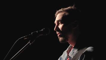 A musician is playing guitar on a large stage with audience members holding flashlights in the background. The auditorium is filled with beautiful flashing lights. 9 video
