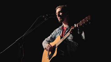A musician is playing guitar on a large stage with audience members holding flashlights in the background. The auditorium is filled with beautiful flashing lights. 31 video