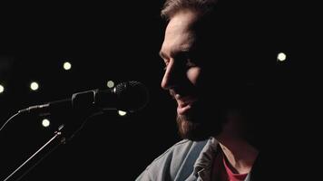 A musician is playing guitar on a large stage with audience members holding flashlights in the background. The auditorium is filled with beautiful flashing lights. 51 video