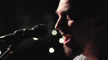 A musician is playing guitar on a large stage with audience members holding flashlights in the background. The auditorium is filled with beautiful flashing lights. 48 video