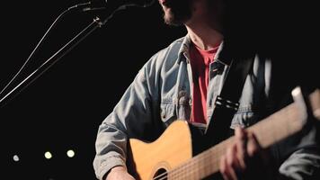 A musician is playing guitar on a large stage with audience members holding flashlights in the background. The auditorium is filled with beautiful flashing lights. 38 video