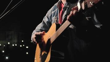 A musician is playing guitar on a large stage with audience members holding flashlights in the background. The auditorium is filled with beautiful flashing lights. 11 video