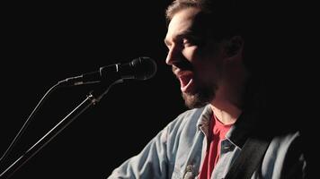 A musician is playing guitar on a large stage with audience members holding flashlights in the background. The auditorium is filled with beautiful flashing lights. 36 video