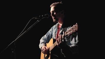 A musician is playing guitar on a large stage with audience members holding flashlights in the background. The auditorium is filled with beautiful flashing lights. 37 video