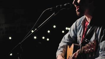 A musician is playing guitar on a large stage with audience members holding flashlights in the background. The auditorium is filled with beautiful flashing lights. 45 video