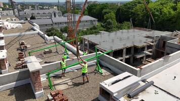 Construction workers installing safety rails on rooftop. Team of workers in safety vests assembling green safety railing on rooftop of a high-rise building video