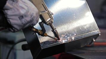 Spot welding sheet metal in factory setting. Close-up of a worker using a spot welding tool to join sheet metal parts, with sparks flying during the welding video