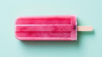 A vibrant pink popsicle on a light blue background. photo