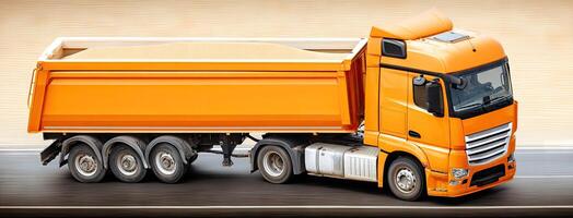 A large orange dump truck driving down the road photo