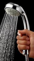 A person stands in a contemporary bathroom, gripping a shower head as it releases gentle streams of water during daylight hours photo
