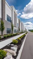 Modern industrial building with a landscaped walkway under a clear blue sky observed from the pavement on a sunny day photo
