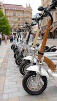 A row of electric scooters parked on a sidewalk photo