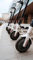 A row of electric scooters are lined up on the sidewalk photo
